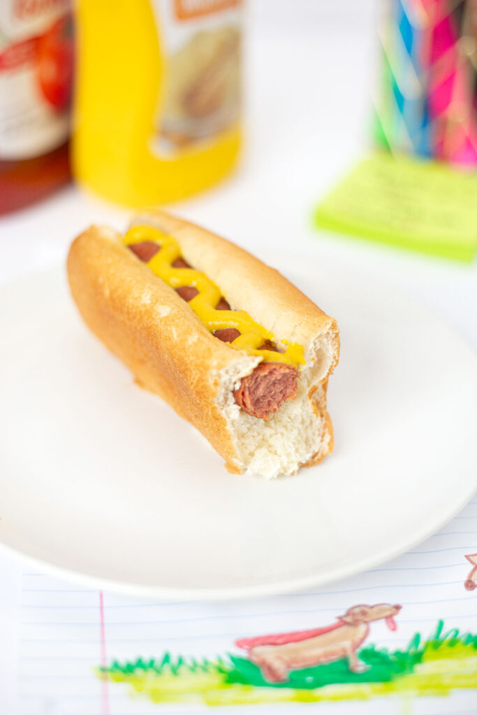 Microwave Hot Dog wiener on bun with mustard with bite removed