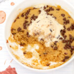 Microwave Molten Chocolate Chip Cookie in bowl with scoop removed, topped with ice cream