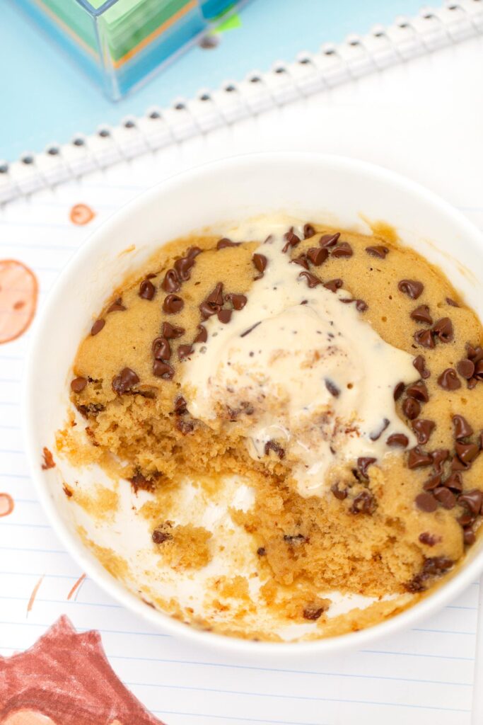 Microwave Molten Chocolate Chip Cookie in bowl with scoop removed, topped with ice cream
